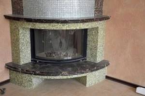 Decorating a fireplace with mosaics is especially good on round shapes, where it is very problematic to use other materials.