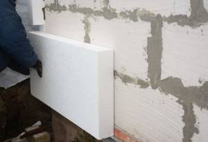 A worker attaches a foam panel to a wall