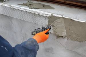 A worker applies an insulating mixture with a spatula to a wall
