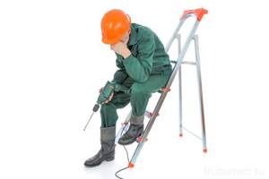 builder sitting with a drill on a stepladder